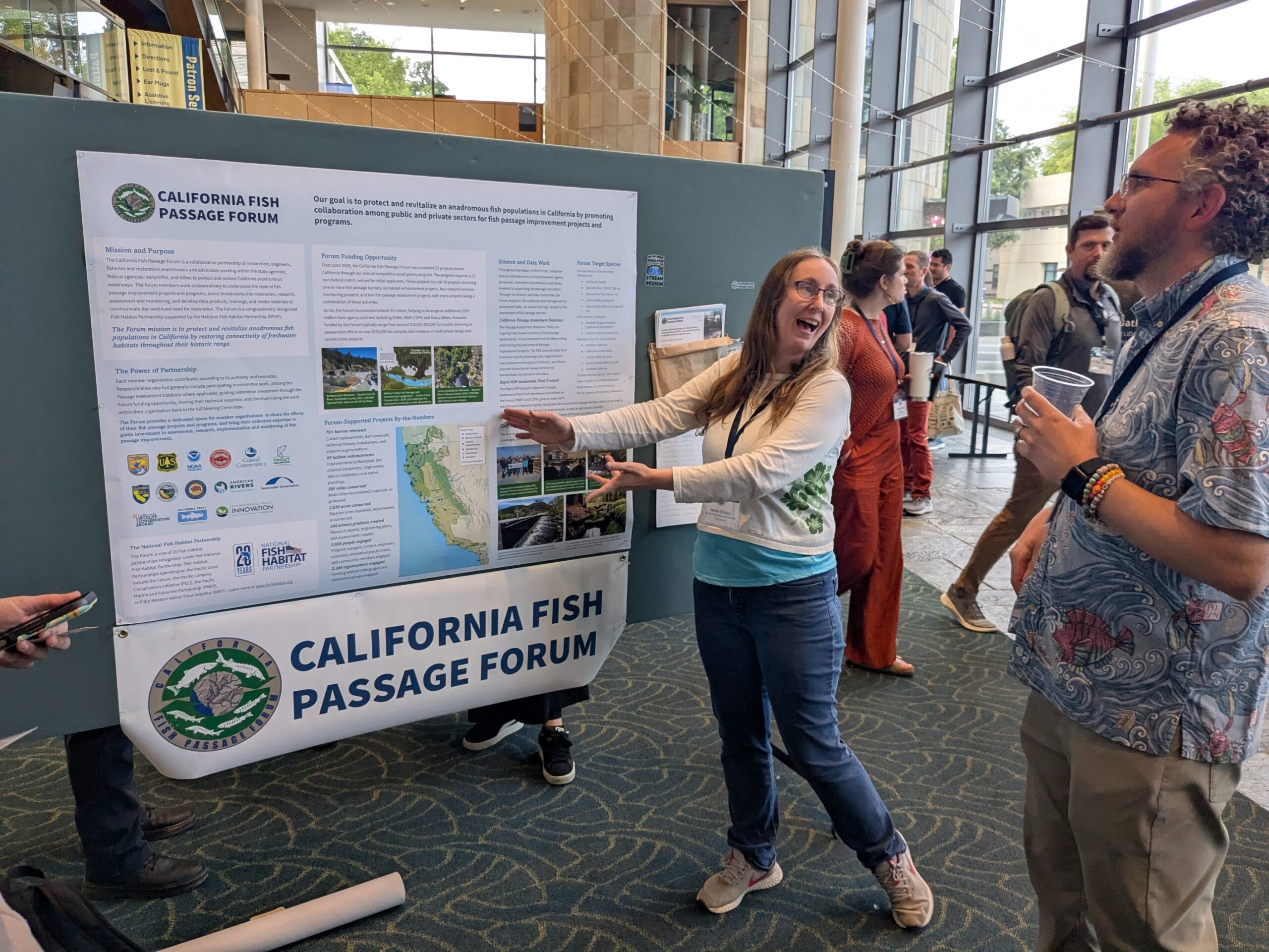 A forum member cheerfully presents information on the forum at a conference poster session