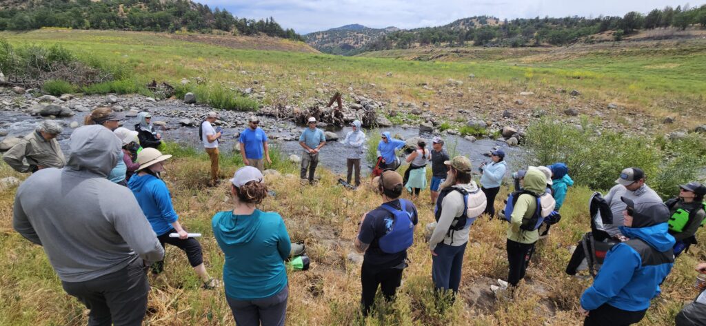 The California Fish Passage Forum members gather in a circle beside Jenny Creek on the Klamath river.